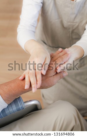 female nurse massaging arthritic hands of elderly man at retirement community center.