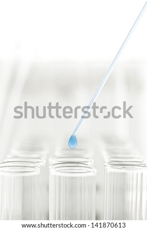 Close-up of a pipette to drop the sample into a test tube of blue.