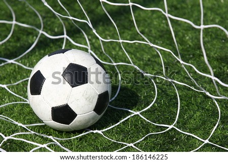 closeup of a black and white soccer ball in  net on a soccer pitch