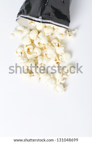 Popcorn from above long shot from above. a bag of white cheddar popcorn spills out of a bag. macro shot on white background in studio.