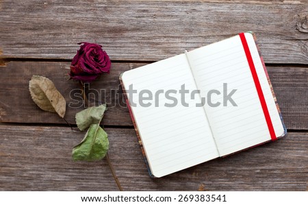 dried rose and open book on the wooden table