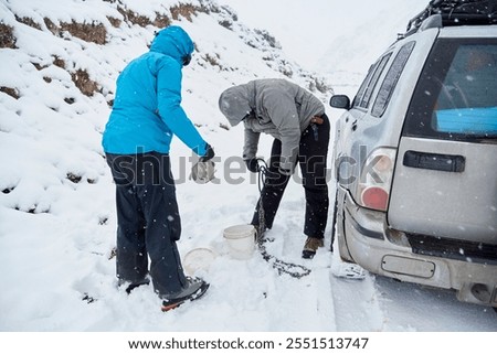Image, Stock Photo Woman putting security snow chain in tire wheel of car