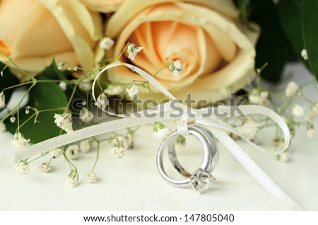 Engagement and wedding rings with bouquet of flowers