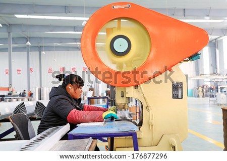 TANGSHAN - DECEMBER 22: worker in operating machinery on the production line, in a solar equipment production workshop on december 22, 2013, tangshan, china.