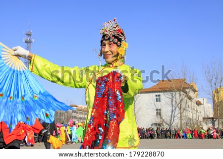 LUANNAN COUNTY, CHINA - FEBRUARY 9: Old man wearing colorful clothes, performing yangko dance in the street, during the Chinese Lunar New Year, February 9, 2014, Luannan County, Hebei Province, China.