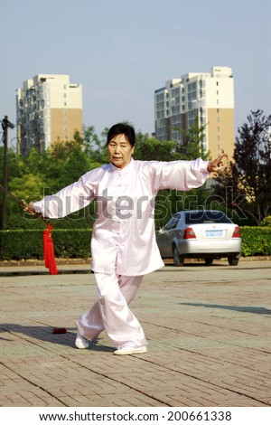 LUANNAN COUNTY - JUNE 14: An old lady was performing Taiji sword on the gym in the square, on june 14, 2014, LuanNan county, hebei province, China