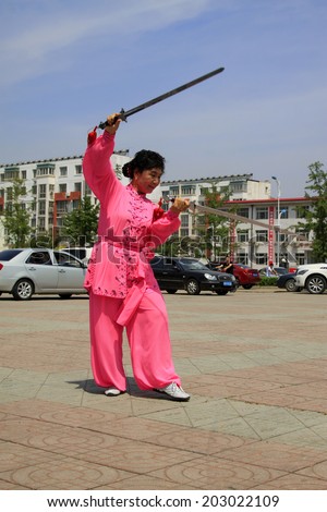 LUANNAN COUNTY - JUNE 29: woman in red was performing fencing in the square, on june 29, 2014, LuanNan county, hebei province, China