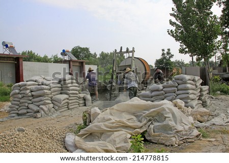 LUANNAN COUNTY - AUGUST 15: bags of cement and concrete mixer in the construction site, on august 15, 2014, Luannan County, Hebei Province, China