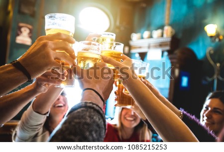 Group of happy friends drinking and toasting beer at brewery bar restaurant - Friendship concept with young people having fun together at cool vintage pub - Focus on middle pint glass - High iso image 商業照片 © 