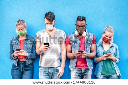 Multiracial friends with face masks using tracking app with mobile smart phones - Young milenial people watching content on social media networks - New normal lifestyle concept - Bright vivid filter