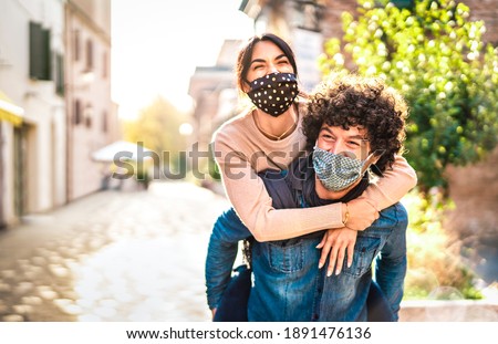 Happy couple of lovers enjoying time outdoor at Valentines day - Handsome guy with nice girl on piggy back moment - New normal love concept with boyfriend and girlfriend together on warm vivid filter
