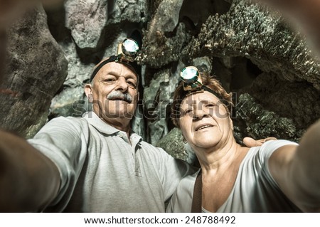 Senior happy couple taking a selfie at the entrance of Tham Phu Kham in Vang Vieng - Adventure travel in Laos and asian destinations - Concept of active elderly around the world with new technologies