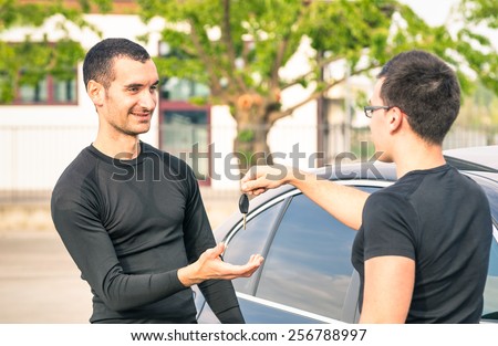 Happy satisfied young man receiving car keys after second hand sale - Concept business transport trade of modern luxury vehicles - Car rental assistance and customer care - Focus on man at left