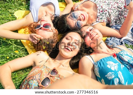 Multiracial girlfriends taking selfie at countryside picnic - Happy friendship concept and fun with young people and new technology trend - Sunny afternoon color tones - Framed hand holding smartphone