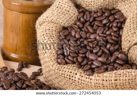 coffee bean in bag and coffee grinder on brown wooden background