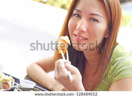 Portrait of a beautiful Asian woman having fresh sushi. Horizontal Shot.