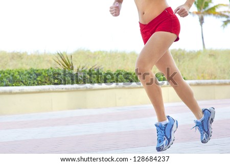 Low section of a fitness woman jogging early morning. Horizontal Shot. Miami Beach, Florida.