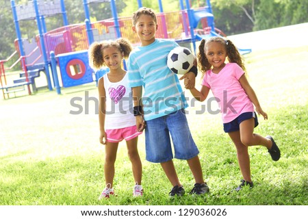 Full length portrait of happy little children with soccer ball at park. Horizontal shot.