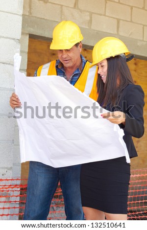 Architect and foreman reviewing blueprint together at construction site.