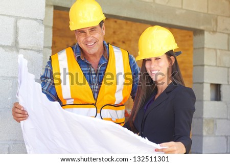 Architect and foreman reviewing blueprint together at construction site.