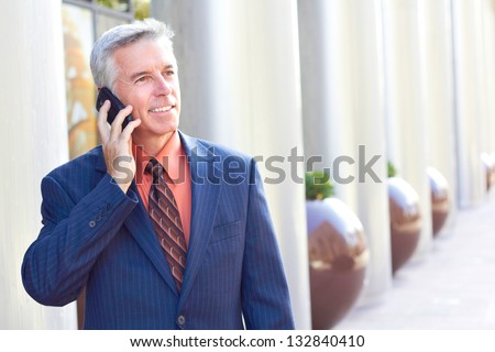 Mature businessman looking away while talking on cell phone. Horizontal shot.