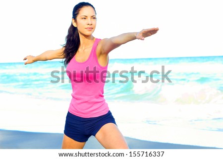 Beautiful female at beach doing yoga warrior pose looking over her right arm for perfect alignment, clearing her mind from the day, stress free