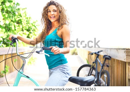 Bike riding female taking a break on boardwalk smiling. Horizontal shot, copy space, color image, pretty yoga female on bike.