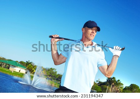 Mature man holding golf club on course against clear blue sky