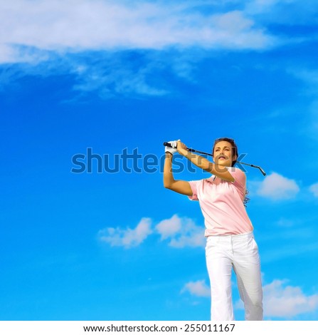 Low angle view of young woman swinging golf club against blue sky