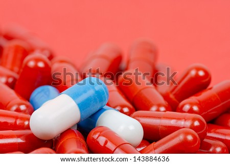 Blue and white pills on background of red pills