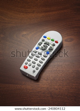 A remote control on a wooden background used for controlling televisions and other electronic devices