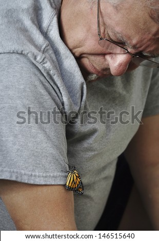 Old man watching a new born monarch butterfly climb up his arm