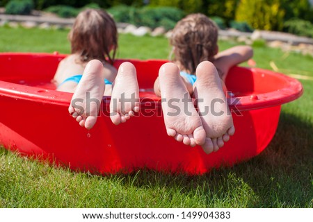 Close-up of feet two sisters in small pool