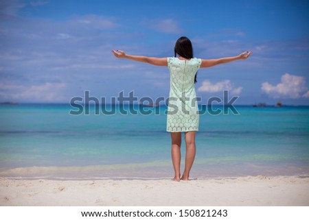 Back view of beautiful girl in dress walking like a bird on the beach