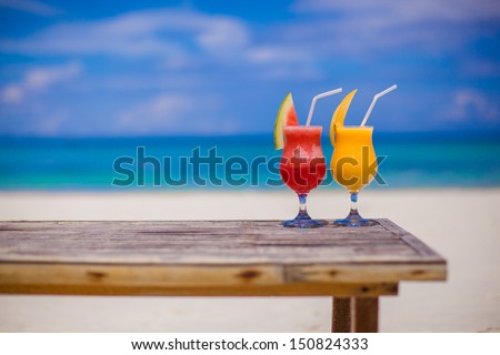 Fresh watermelon and mango cocktails on woodem table background of stunning turquoise sea