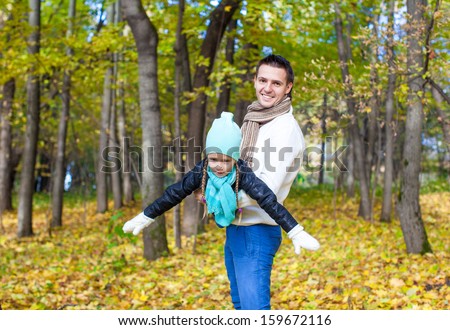 Happy dad and little daughter having fun in the park on sunny autumn day