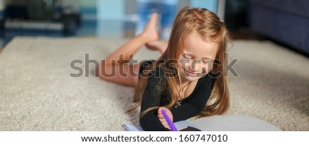 Portrait of a sweet charming young girl who draws with his coloring at home