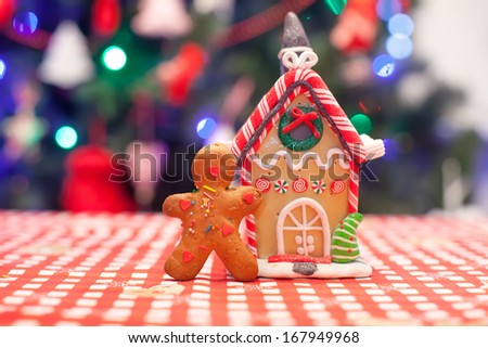 Cute gingerbread man in front of his candy ginger house background the Christmas tree lights