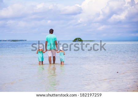 Back view of adorable little girls and young father walking at exotic island