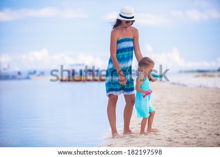 Little girl and young mother walking on tropical beach in desert island