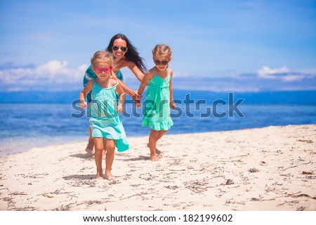 Adorable little girls and young mother have fun on tropical white beach in desert island