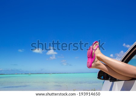 Close up pink flip flops from a car background of tropical beach and blue sky