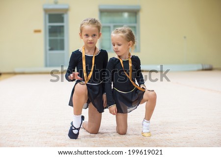 Two little gymnasts in the gym with medals