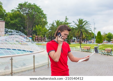Young man using telephone with map in hands