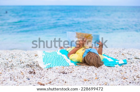 Adorable little girl with big map on tropical beach vacation