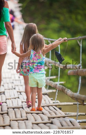 Young mother with her little girls on suspension bridge over the River