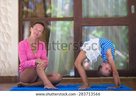 Young woman and little girl engaged in fitness outdoor on terrace