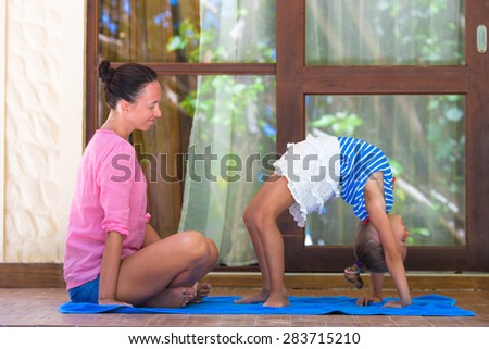 Young woman and little girl engaged in fitness outdoor on terrace