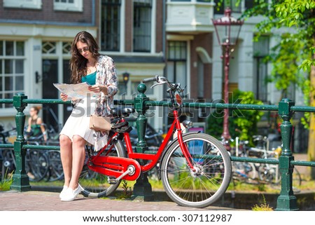 Happy young woman with city map and bikes in european city