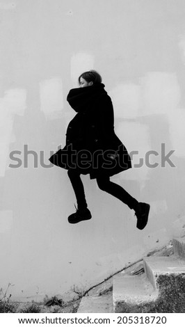 figure of a girl in a black coat flying down the stairs